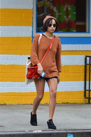 Zoe Kravitz walking in shorts and an orange top