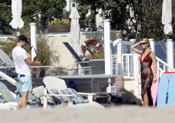 Paris Hilton at the beach in a skimpy red bikini and fishnet kaftan in Malibu.July 12, 2013