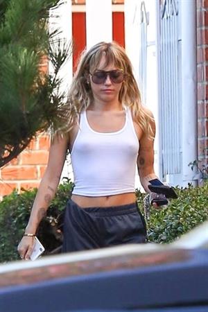 Miley Cyrus braless boobs in a slightly see through white top showing off her tits seen by paparazzi.
