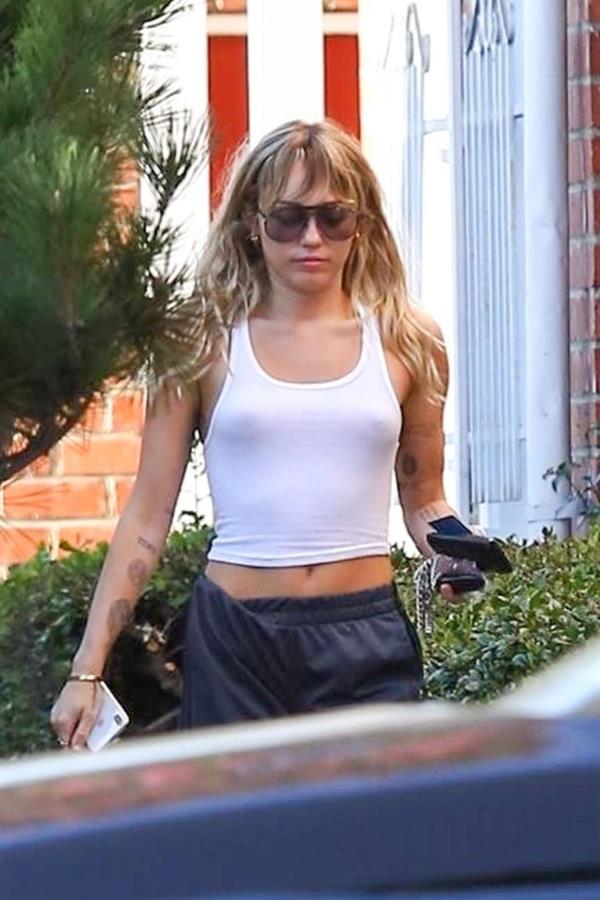 Miley Cyrus braless boobs in a slightly see through white top showing off her tits seen by paparazzi.
