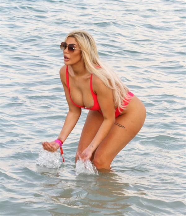 Chloe Ferry areola peeks wardrobe malfunction in a thong bikini showing off her ass and flashing her tits, ass, and cleavage seen by paparazzi at the beach.
