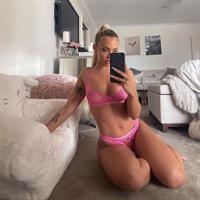 Tammy Hembrow boobs showing nice cleavage with her her tits in see see through lingerie sitting in her living room in matching pink bra and panties.