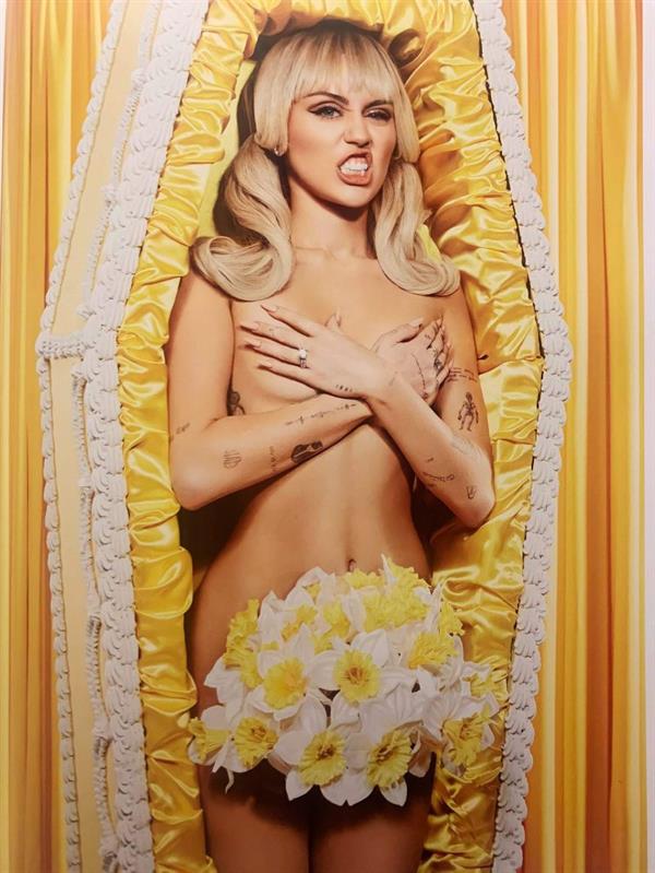 Miley Cyrus nude new photo posing in a coffin covering her topless boobs.