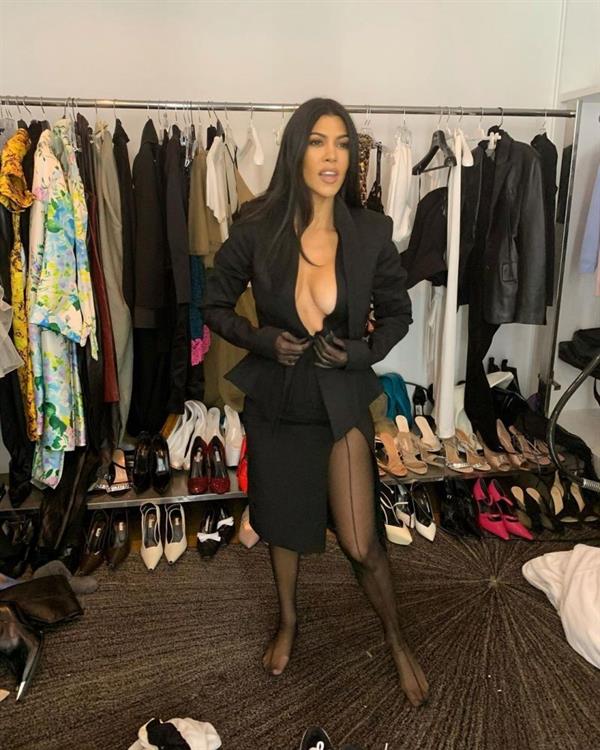 Kourtney Kardashian braless boobs showing nice cleavage with her big tits in an open black jacket while she is getting dressed.
